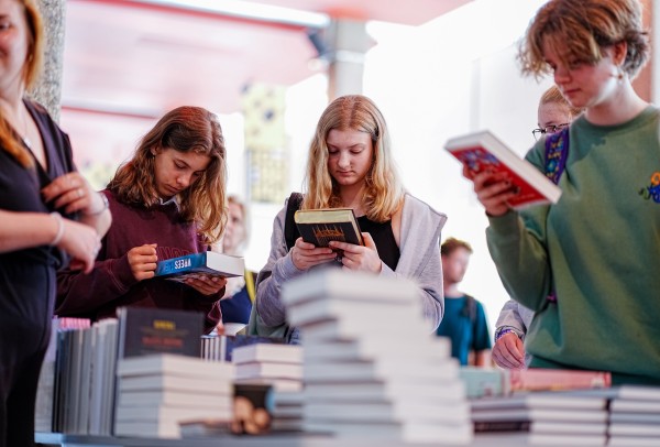 Drie leerlingen bekijken boeken tijdens de Dag van de Jonge Jury in de Doelen te rotterdam op 9 juni 2022.